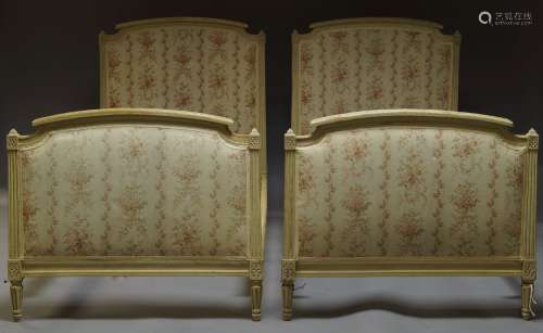 A pair of Louis XVI style cream painted single beds, early 20th Century, with floral upholstered