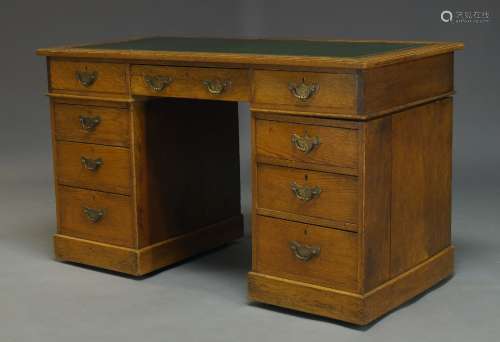 An oak pedestal desk, late 19th Century, the rectangular top inset with green leather writing