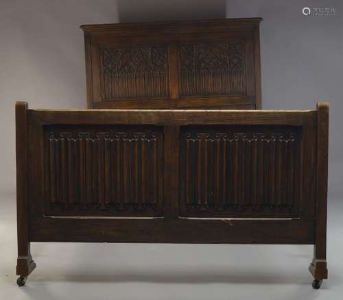 An oak bed in the Gothic taste, early 20th Century, the panelled headboard with carved Gothic arches