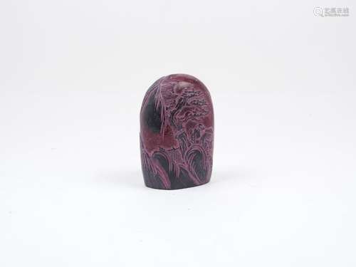 A Chinese red stone seal, of rounded form with decorative carving to the sides depicting a landscape