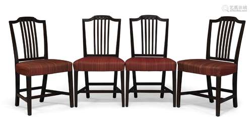 A set of four George III mahogany dining chairs, the shaped crest rails with carved rosettes above