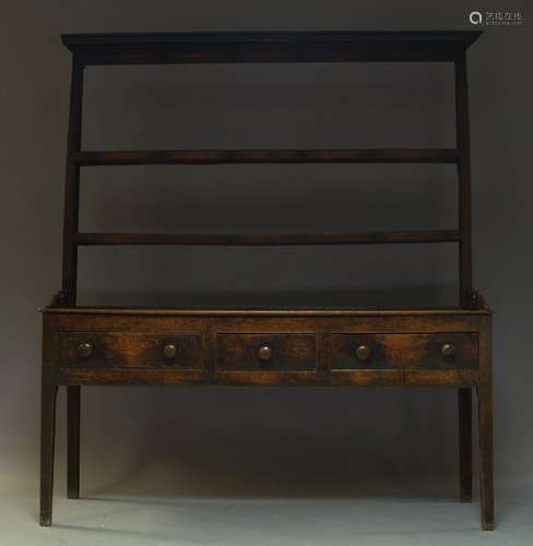 A George III oak dresser, the plate rack with moulded cornice above two shelves, the base with three