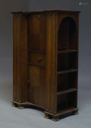 An oak secretaire cabinet, c.1930, the shaped top above fall enclosing writing surface and three