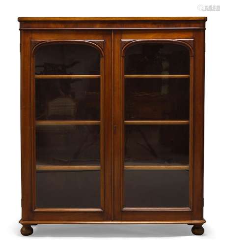 A Victorian mahogany bookcase, with two glazed cupboard doors enclosing three shelves, raised on bun