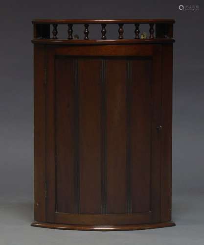 A mahogany corner cupboard, early 20th Century, of bow front form, the galleried top above