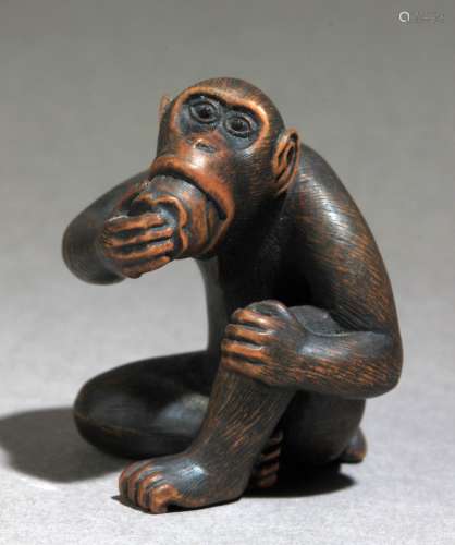 Netsuke japonés约1848-1922年。明治时期。牢固的正直二世在基地。漆黑的瓷器，代表着一个单体的送信人，带着卵石，带着一个果实，40,5x34,2x35,4 mm.11,79 gr.大约1848-1922年的明治时期的日本网助。底座上有正直二世的签名。雕刻木雕的坐猴角眼，正在吃水果，40,5x34,2x35,4毫米。11,79克。