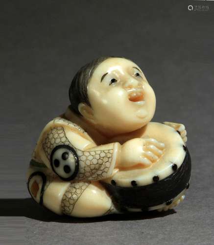 Netsuke japonés tipo mosaico约1900年。明治时期。坚定的安明在一个汉字玫瑰色的基础上。在marfil policromado con incrustaciones representando niño sentado en el suelo tocando un tambor, 24,4x26,6x21,2 mm.9,91 gr.Se adjunta documento de peritación expedido por la Federación Española de Anticuarios.约1900年明治时期的日本马赛克式网架。底部的红色汉字上有安明的签名。雕刻和镶嵌的象牙，描绘了一个坐在地上打鼓的孩子，24,4x26,6x21,2毫米。9,91克。附西班牙古董商联合会出具的专家报告。