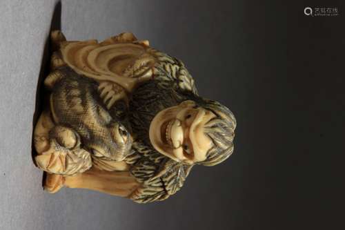 Netsuke japonés约1800-1825年。江户时代。Sin firmar.在大理石卷轴上代表Gama Sennin sentado en el suelo cogiendo la pata de un sapo que se haya sobre su pierna izquierda, 39,6x33,3x21,6 mm.18,33 gr. Se adjunta documento de peritación expedido por la Federación Española de Anticuarios.一件来自江户时期的日本网架，约1800-1825年。雕刻的象牙描绘了一个坐在地上抓住蛤蟆腿的伽玛仙人，39,6x33,3x21,6毫米，18,33克。18,33克，附西班牙古董商联合会出具的专家报告。