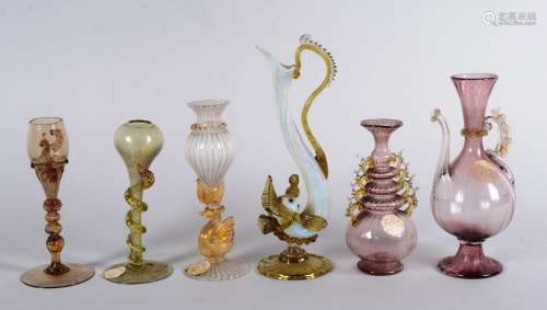 穆拉诺--威尼斯--19世纪。六（6）个穆拉诺玻璃杯套装。- 一把壶上的皮杜切和镀金。高：15.5厘米- 索利弗洛花瓶，有连续的双色环。高：12厘米- 球茎瓶，蛇的盘脚。高：12.5厘米- 卵形小瓶，金字牌，圆底白丝。高：14厘米- 海豚形状的多色水壶。高：20厘米- 小玻璃杯。两个把手都出事了。高：13厘米