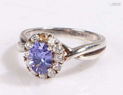 Sterling silver ring, the head set with a central blue stone surrounded by a band of cubic zirconia,