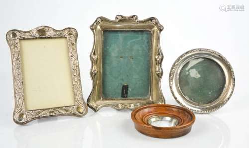 Three silver photograph frames, one embossed with scrollwork decoration.