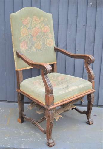 An 18th century walnut armchair, with tapestry back and seat, the arms carved with decoration.