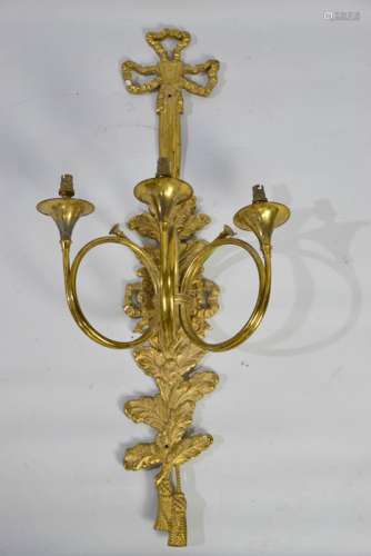 A French brass wall light with three branches in the form of French horns, on a foliate back with