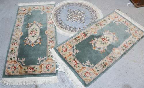 A circular wool rug together with a pair of modern rugs with green ground and floral pattern, 94cm