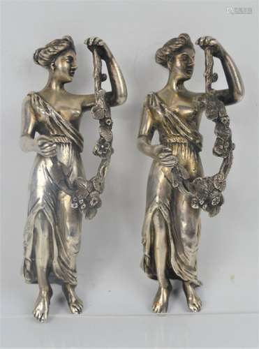 A pair of silver plated female figurines holding floral swags, 14cms tall