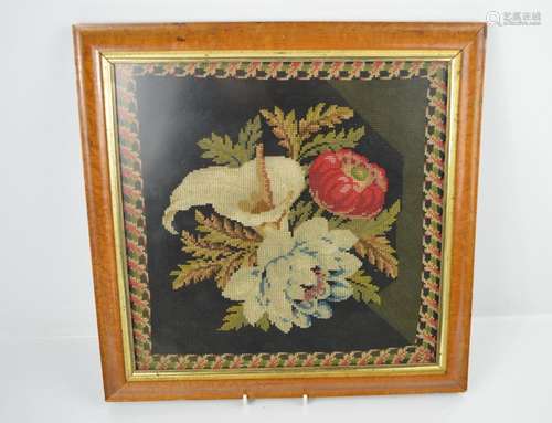 A 19th century needlework picture depicting poppies and tulips in a maple frame.