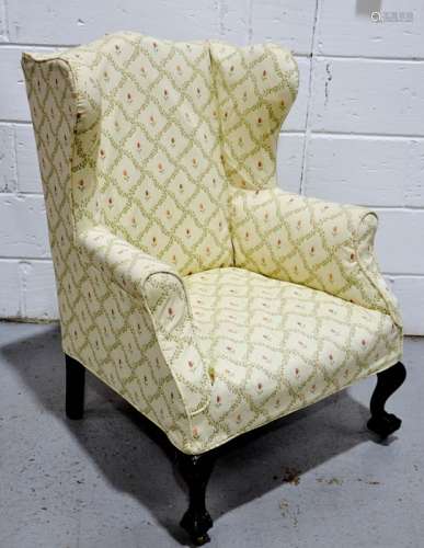 A modern wing back arm chair, with ball & claw feet and cream flowered upholstery.