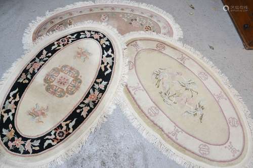 Three modern oval Chinese wool style rugs, one depicting cranes and calligraphy marks 152cm x 90cm