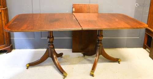 A mahogany twin pedestal dining table, with extra leaf, with brass caps and castors, 182 long,