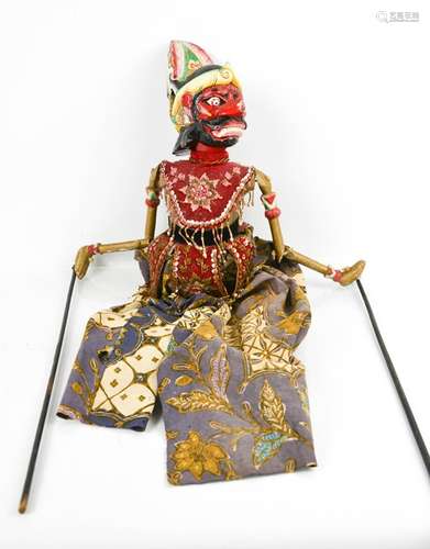 An Indonesian hand painted wooden puppet, with embroidered clothing and silk screen fabric.