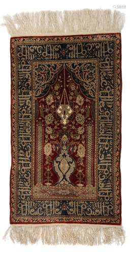 An Oriental silk on silk Hereke rug, decorated with a flower vase, the details finely brocaded with