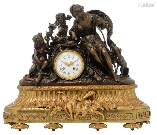 A gilt bronze mantle clock decorated with hunting trophies, with on top a patinated bronze group dep