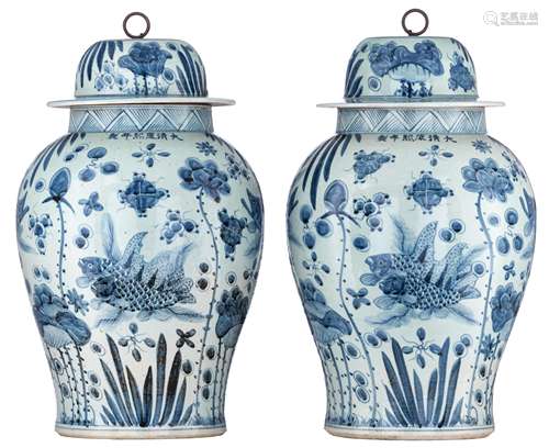 A pair of Chinese blue and white covered vases, decorated with carps in a pond, with a Kangxi mark,