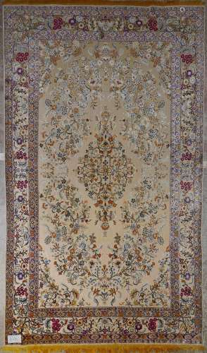 Grand tapis Kirman en soie à décor floral en relief beige, orange, vert et bleu sur fond orange clair. Travail persan. Epoque: vers 1920 - 1930. Dim.:+/-353x222cm.