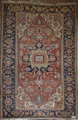 Grand tapis Heriz en laine fait main décoré d'un médaillon central floral géométrisé rose, bleu foncé, bleu clair et beige sur fond floral géométrisé rouge et beige. Travail perse. Dim.:+/-461x286cm.