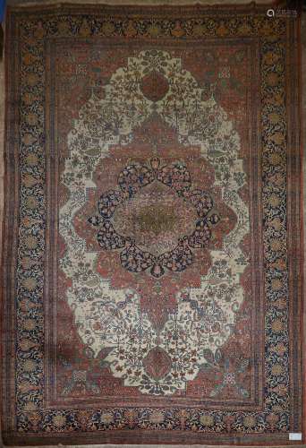Grand tapis Tabriz en laine fait main décoré d'un grand médaillon floral stylisé beige, vert, rouge et bleu sur fond beige et rouge. Travail persan. Dim.:+/-557,5x365cm.