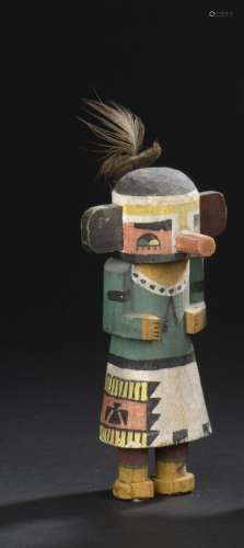 Poupée Kachina Talavai, Hopi, ArizonaH. 16 cmPetit personnage debout, le buste recouvert de pigments verts, collerette blanche animée d'une succession de petits points noirs et d'un noeud simple. Sur le côté droit de la manta blanche apparaissent de jolis motifs géométriques polychromes. Les yeux sont délicatement magnifiés par un subtil assemblage de couleurs et des arcades sourcilières noires épaisses. Le pourtour rouge, met en valeur le trait noir délimitant le regard et les cils inférieurs finement suggérés. Originalité de cette poupée présentant deux pupilles dans chaque oeil; l'une jaune l'autre verte. Une arête médiane jaune horizontale anime le front. Quelques plumes de sa coiffe sont conservées et apparaissant à l'arrière de son crâne. Fantaisie et singularité des oreilles l'une et l'autre de couleurs différentes. Pigments légèrement passés, quelques manques. Expert : Aurore Krier-Mariani