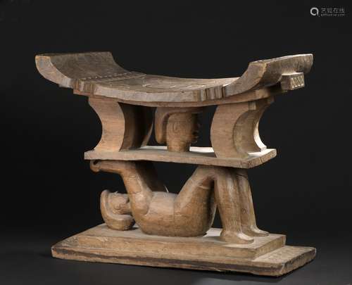 Tabouret de style Ashanti, GhanaL. 63 cm l. 34 cmÉléments caractéristiques de l'assise cérémonielle royale akan : base rectangulaire et plateau incurvé. Deux sujets aux rondeurs et visages réalistes et stylisés sont répartis sur deux niveaux. Un personnage allongé les bras levés supporte un visage au niveau supérieur. Patine claire, d'usage. Décor gravé de formes géométriques.