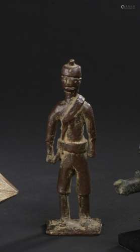 Militaire Dan, Côte d'Ivoire H. 15,5 cm  Petit militaire en bronze arborant une coiffure attestant de son rang, et une ceinture. Allure figée. Manques dus à l'ancienneté.