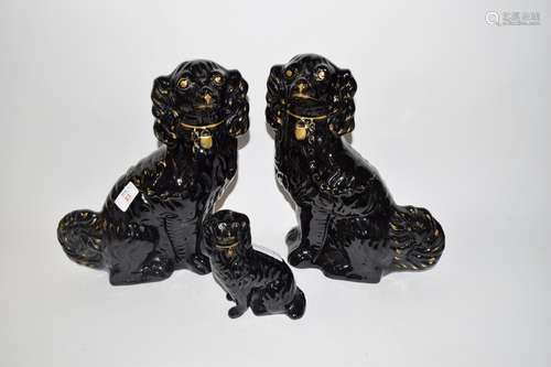 Group of three black Staffordshire spaniels comprising a large pair and smaller model, all with gilt