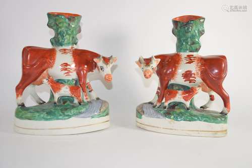 Staffordshire pair of cows with calves modelled as spill holders on oval bases (2)