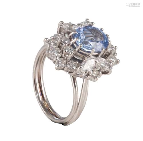 An 18ct white gold ring, central set with an oval cut sapphire and furthermore all-around mounted with brilliant-cut diamonds, total weight 9 g