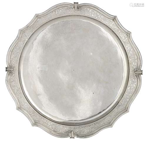 An 18thC circular French Régence silver salver, the gadrooned rim engraved with arabesque decoration, raised on three volute shaped supports, Brussels hallmarks, illegible date mark (crowned O for 1730?) and a ditto m...