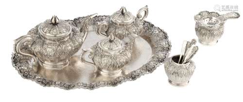 A six-part silver coffee and tea set, ornately decorated with lotus flowers, comprising a coffee pot with bird spout, a teapot with beak spout, a sugar pot with spoon and a tea strainer with holder, and a smaller reci...