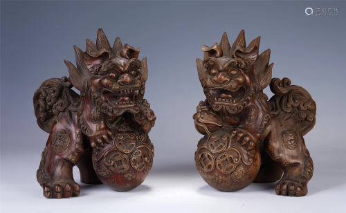 A PAIR OF CHINESE HARDWOOD CARVINGS OF LIONS