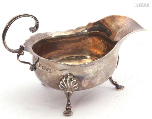Edward VII silver sauce boat of typical form with card cut rim and applied flying C-scroll handle,