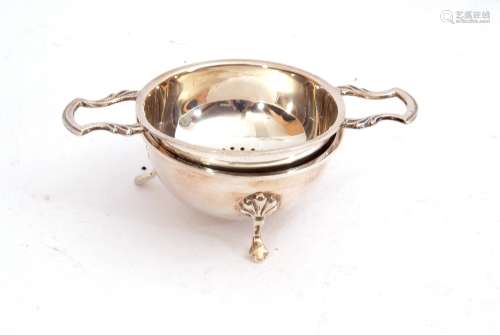 Elizabeth II silver tea strainer and stand, the circular pierced bowl sits between twin angular