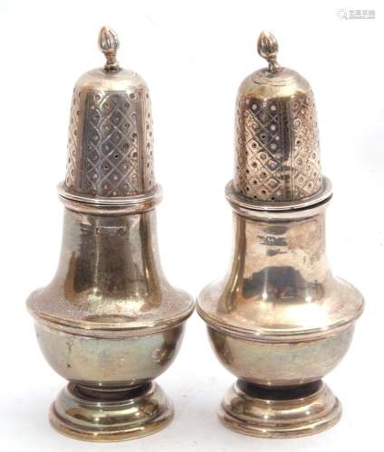 Pair of George V silver peppers having a baluster body, a pierced pull off lid with an urn finial