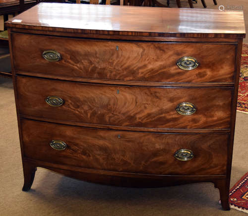 Late Georgian mahogany bow front chest of three drawers with oval embossed brass fittings and raised