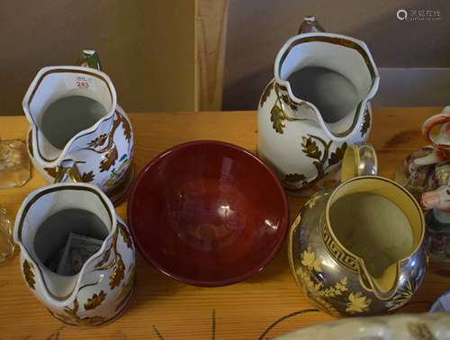 Collection of four Staffordshire jugs with gilt floral design and Prinknash Pottery bowl with red