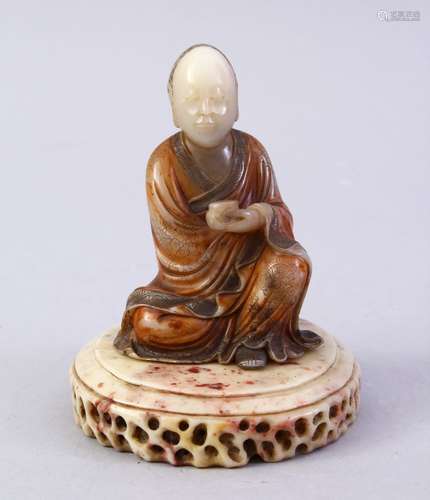 A GOOD CHINESE CARVED SOAPSTONE FIGURE OF ROHAN, in a seated position holding a vessel, with a