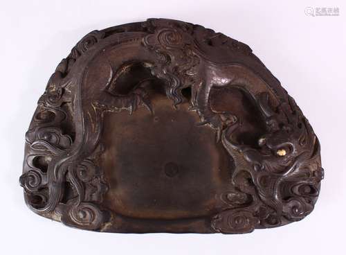 A 19TH CENTURY CHINESE SHAPED INKSTONE, carved with dragons, 23cm x 17cm.