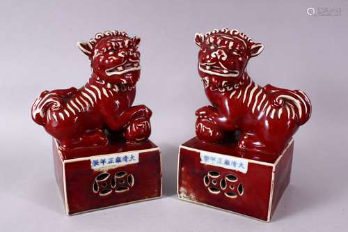 A PAIR OF CHINESE COPPER RED PORCELAIN TEMPLE LIONS, each posed upon a fixed base with their paw