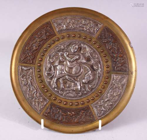 AN INDIAN BRASS CIRCULAR DISH, overlaid with white metal and copper panels, the centre depicting a