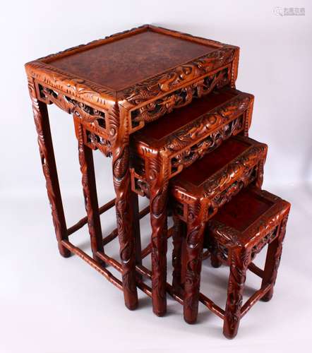 A FINE 19TH / 20TH CENTURY CHINESE CARVED HARD WOOD NEST OF FOUR DRAGON & BAT TABLES, the tops