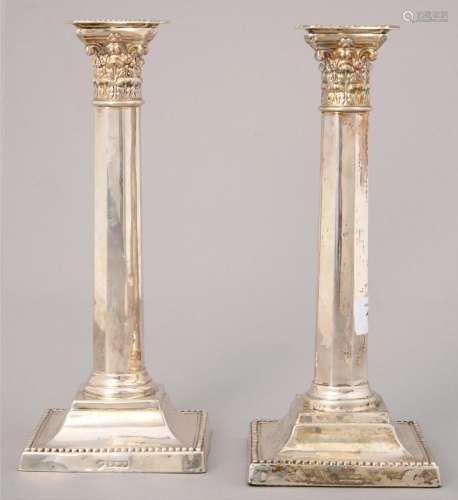 A PAIR OF SILVER COLUMNAR CANDLESTICKS, WITH CORINTHIAN CAPITAL ON BEADED SQUARE FOOT, NOZZLES, 26.